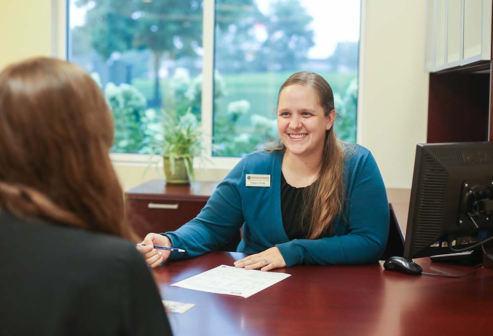 DCCU employee, Bethany, helping a member in a branch office