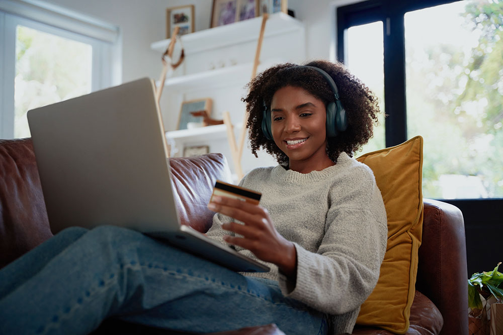 Woman sitting on couch with laptop and credit card