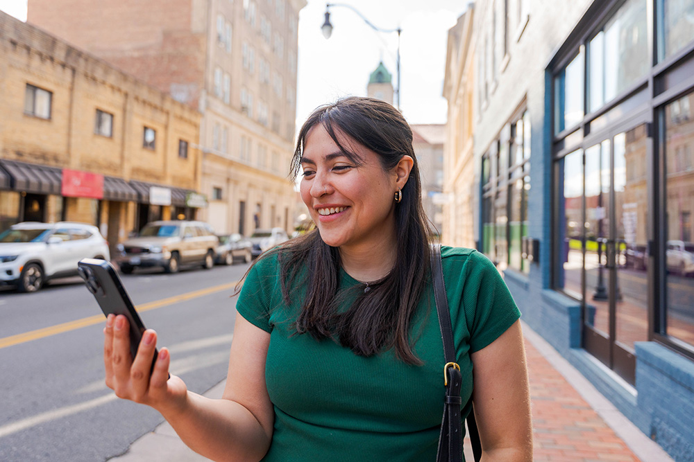 Smiling woman looking at smartphone in downtown Harrisonburg, VA