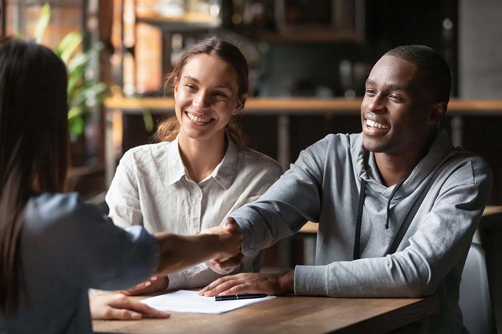 couple shaking hands with advisor at contract signing