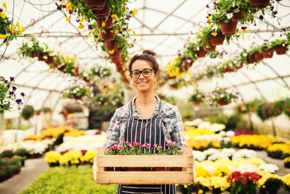 A woman with glasses stands, holding a bunch of flowers. 