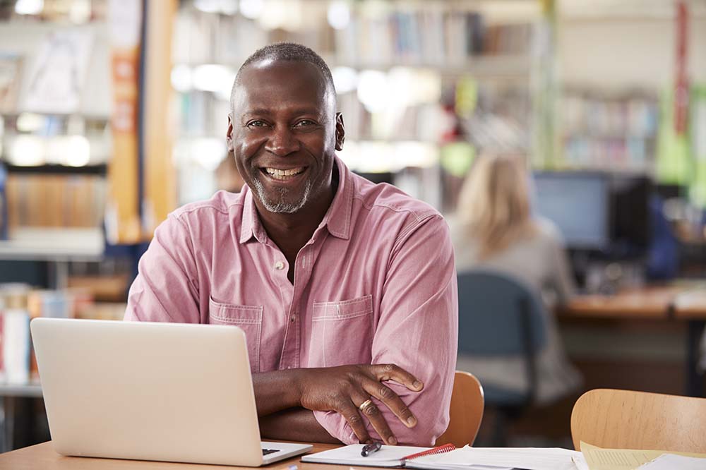 adult student working smiling in front of laptop