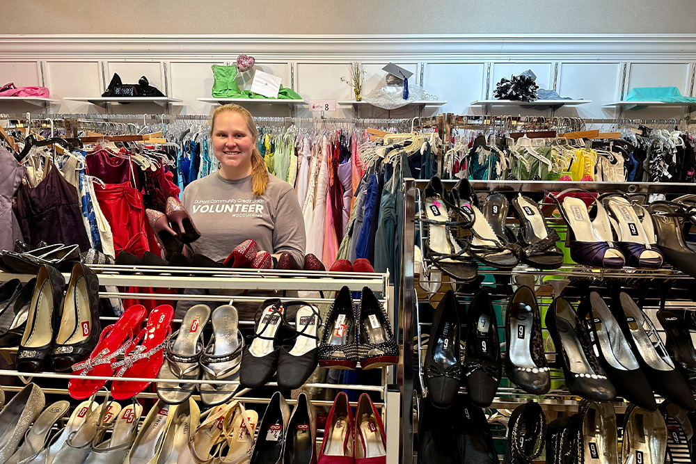 A DCCU employee poses behind a rack of shoes at the Cinderella Project in Harrisonburg, Virginia. 