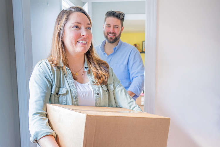 Couple moving boxes into house