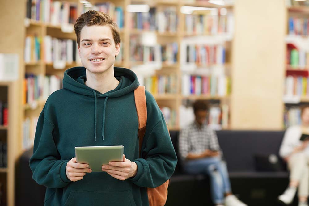 young male student in library smiling