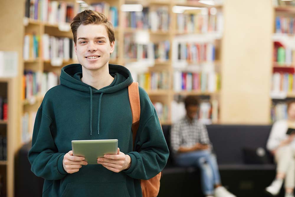 young male student in library smiling