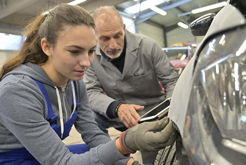 female technical student working on car body