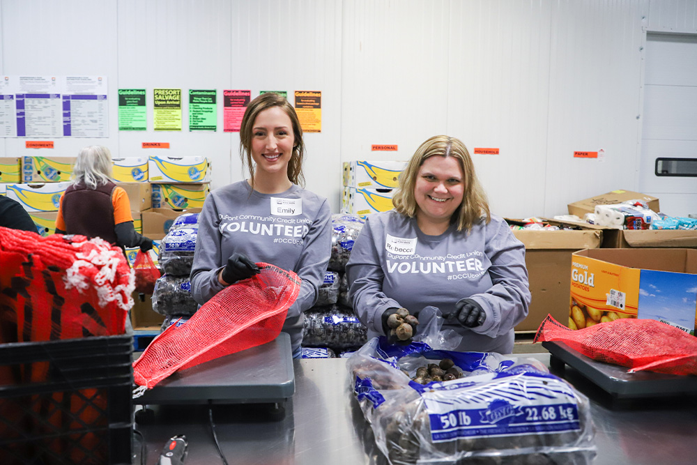 Two female DCCU employees volunteer their time at the Blue Ridge Area Food Bank. 