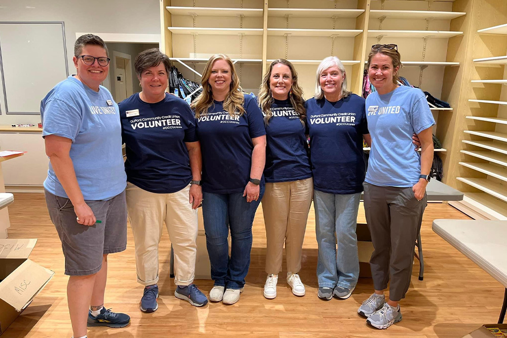 DCCU employees pose for the camera in a vacant storefront  as they volunteer. 