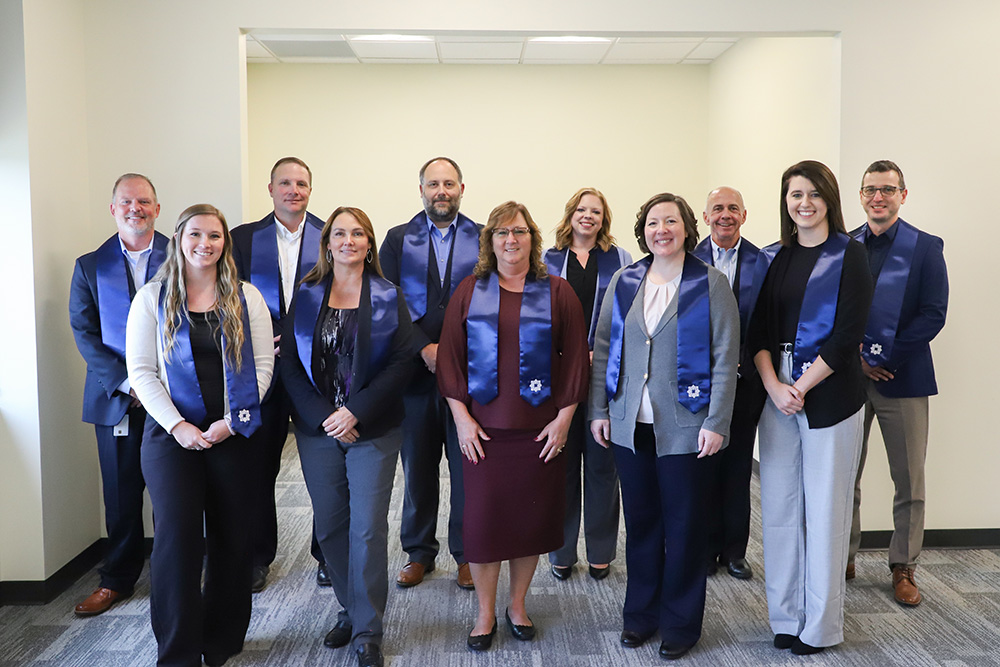 A group of DCCU leaders smile for the camera as they graduate the 2025 Leadership graduation 