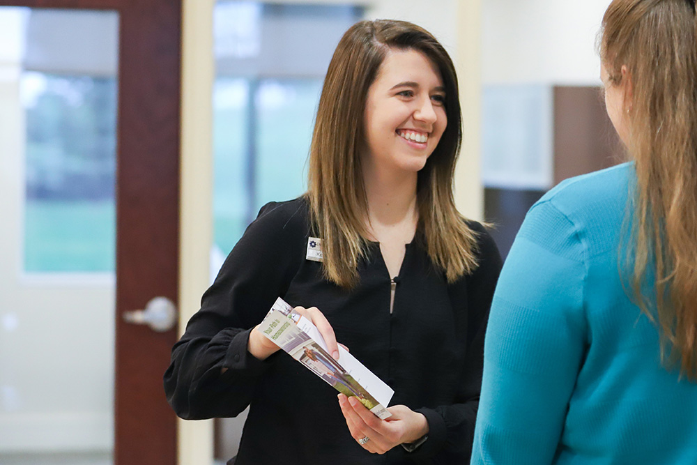 DCCU Woodstock location Assistant Branch Manager, Kendall, explains a brochure to a member
