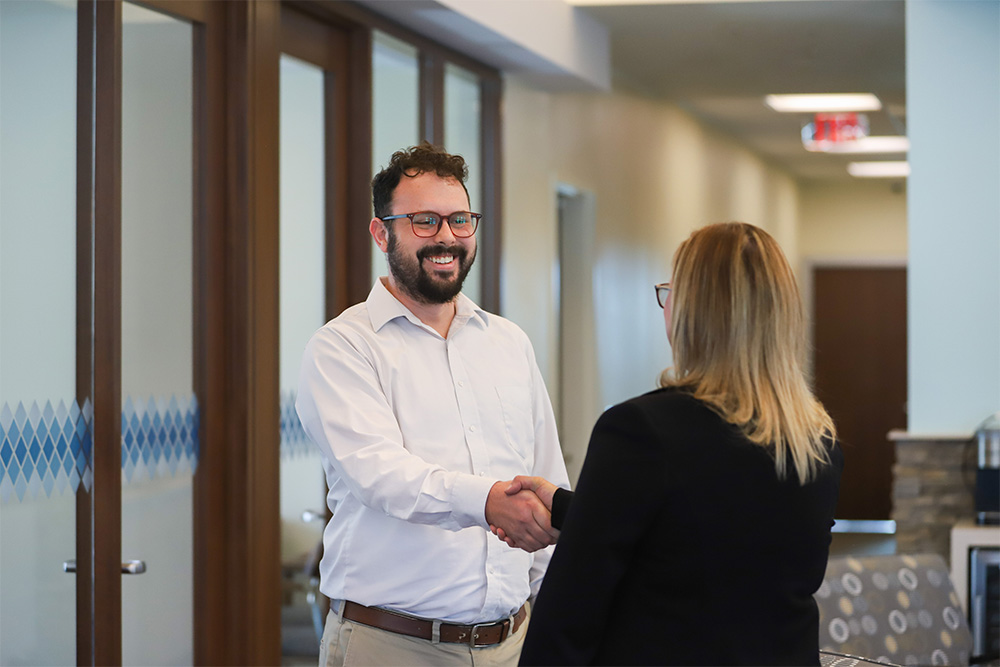 DCCU Sales and Service Trainer, Chris, smiles as he shakes the hand of a member
