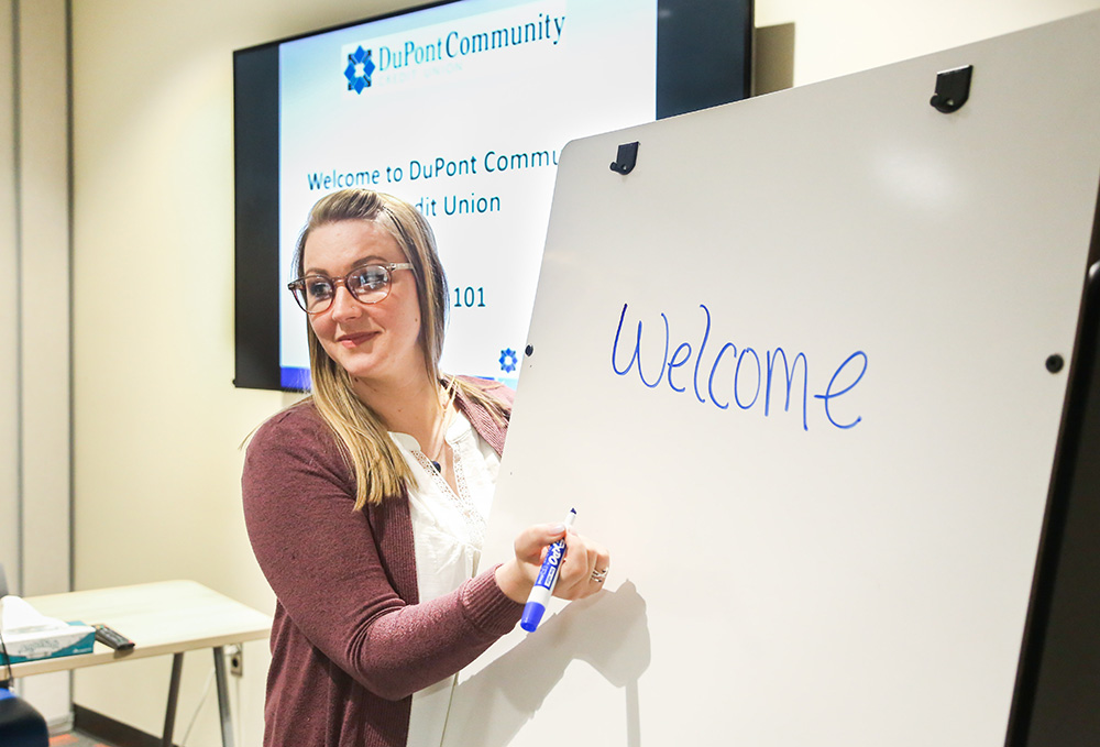 Woman holding dry erase marker in front of white board with 'hello' written on it