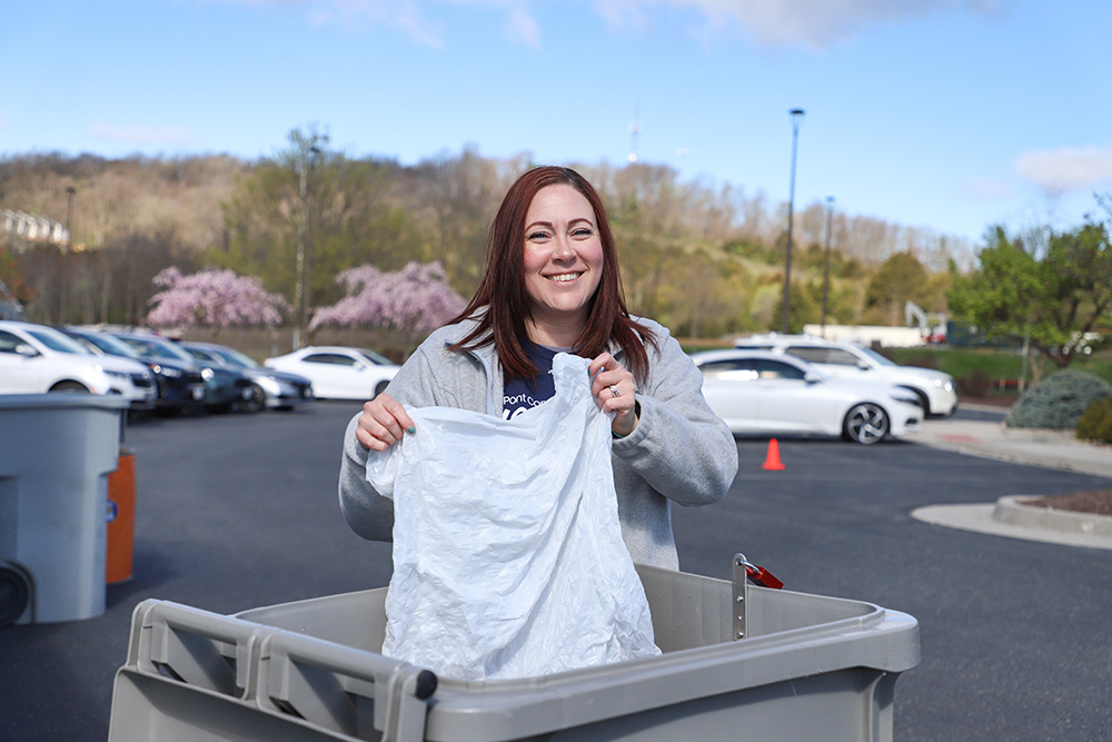 DCCU Member Advisor, April, smiles for the camera as she poses behind a shred bin at the Kaylor Shred Days event in Spring 2024.
