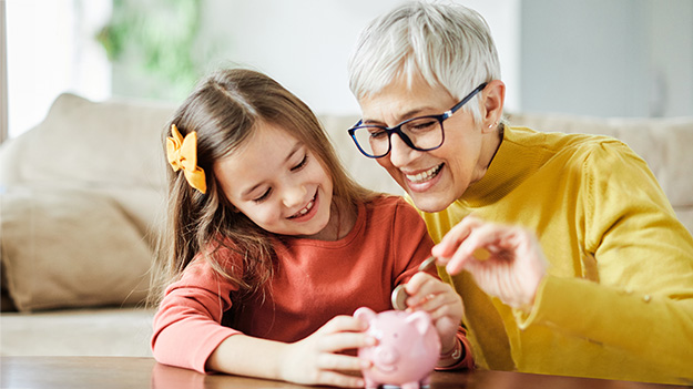Grandparent and child putting money in piggy bank