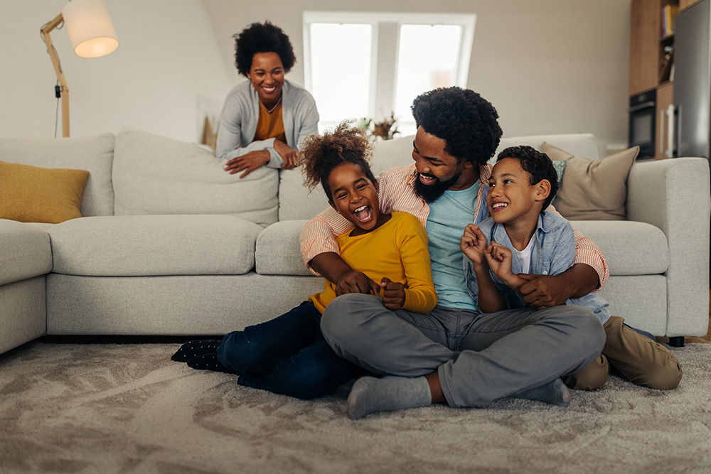 Family of 4 playing in the living room in front of couch