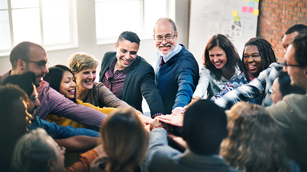 A group of professionals have their hands in a circle together