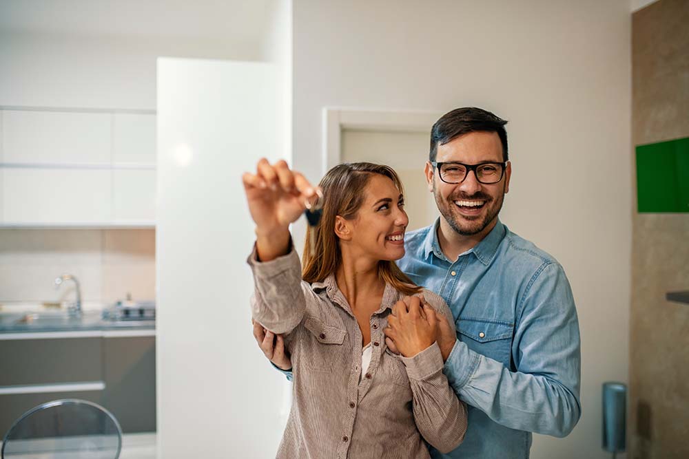 excited couple holding keys to new house