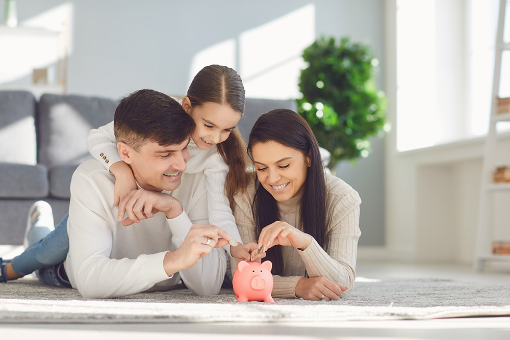 family of three putting money into a piggy bank 