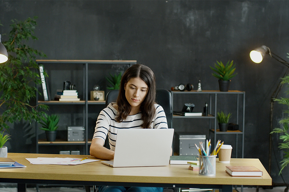 Young woman sits in front of laptop computer at desk