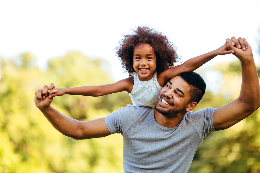 dad and daughter happily playing outside together