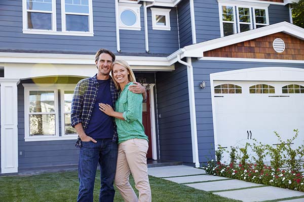 couple standing and smiling in front of new home