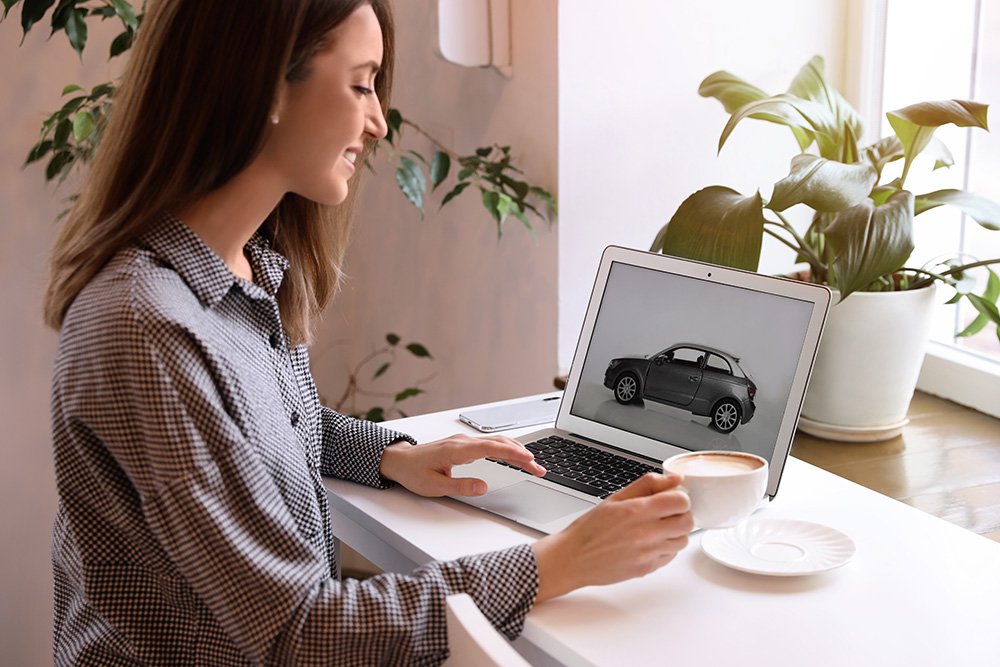 woman shopping for cars online while drinking coffee