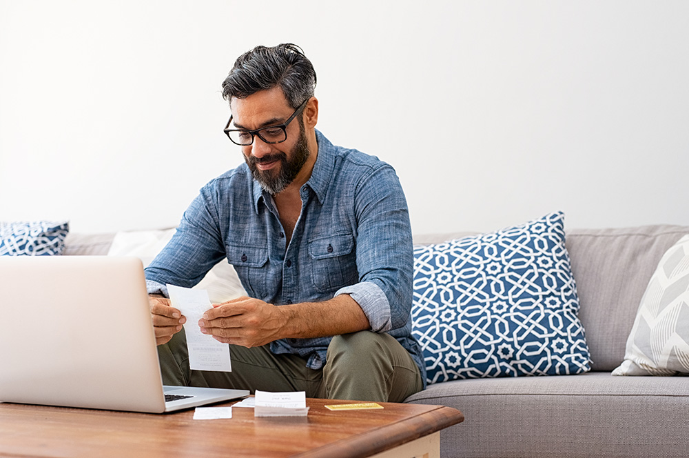 man reviewing receipts and looking at his laptop