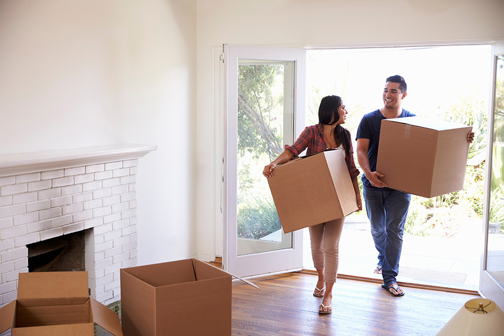 couple moving boxes into new home together