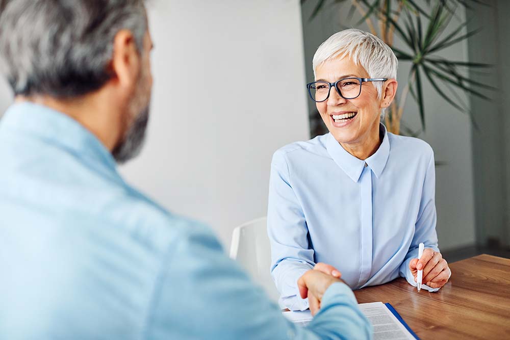 elderly woman shaking hands with financial advisor