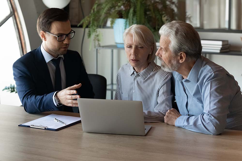 elderly couple meeting with financial advisor in front of laptop