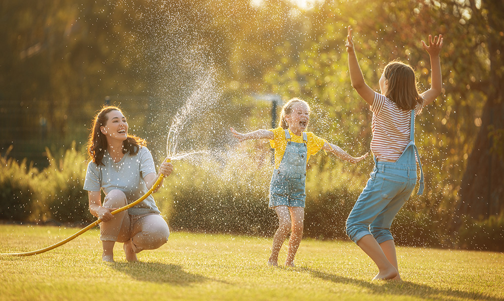 Woman and two young children playing in water in the summer