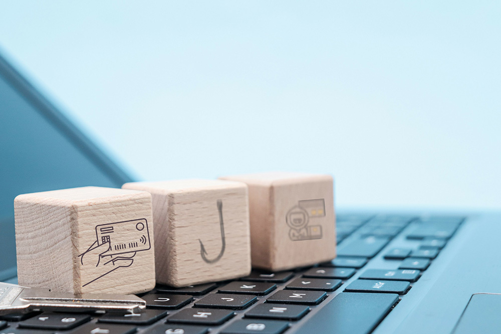 Three wooden blocks bearing cartoon images sit atop the keyboard of a laptop computer