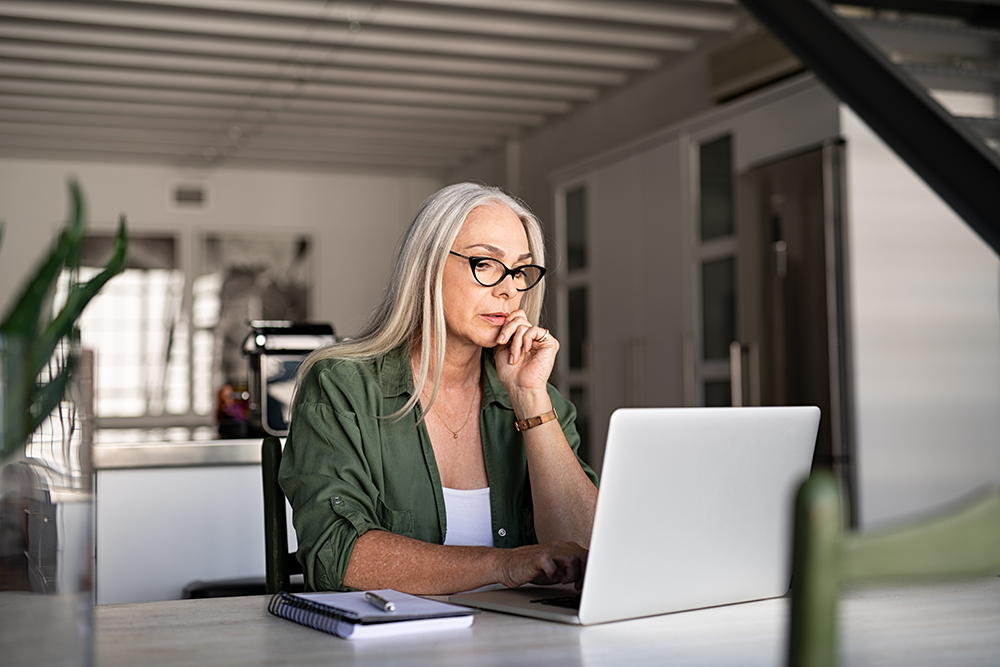 Elderly woman seriously working on laptop