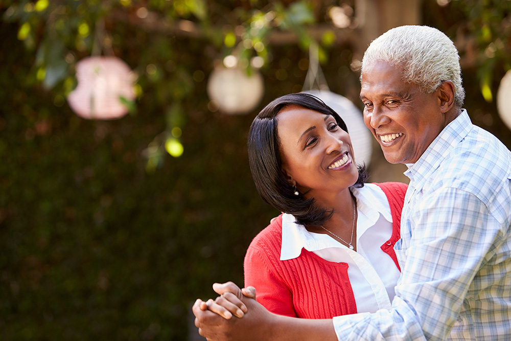 Elderly couple dancing happily in backyard