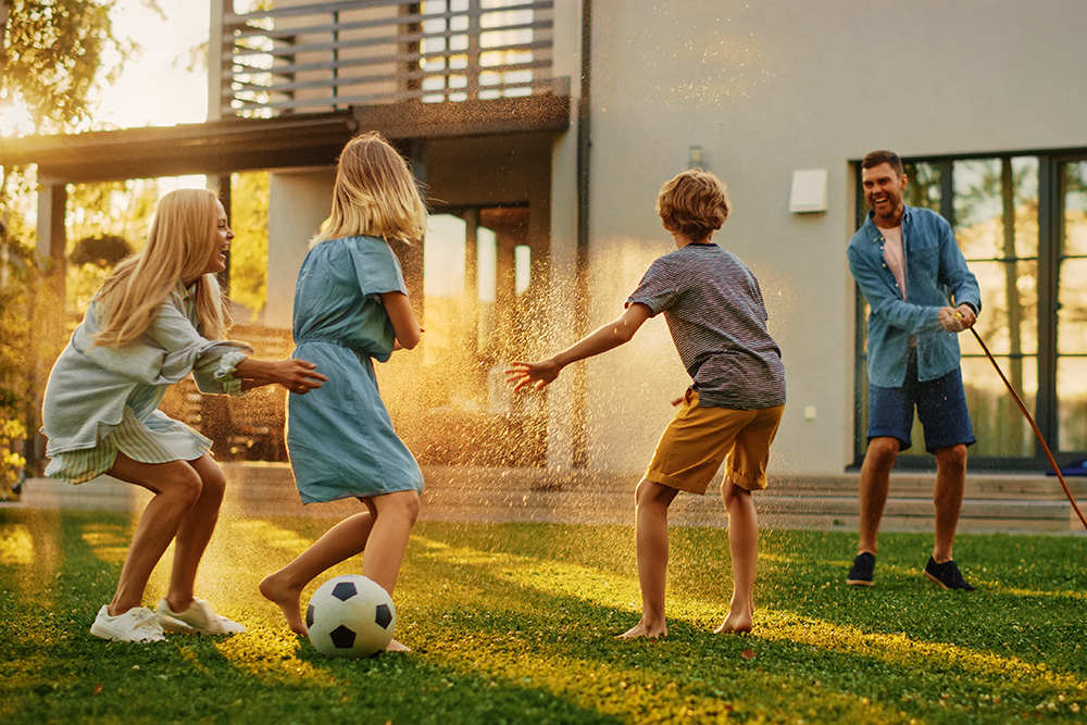 Family playing soccer in their yard in front of house