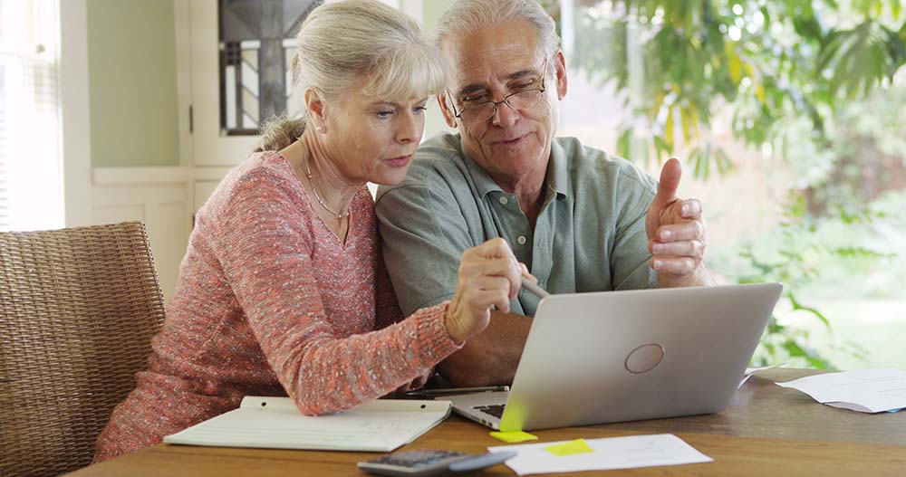 elderly couple looking at laptop concerned