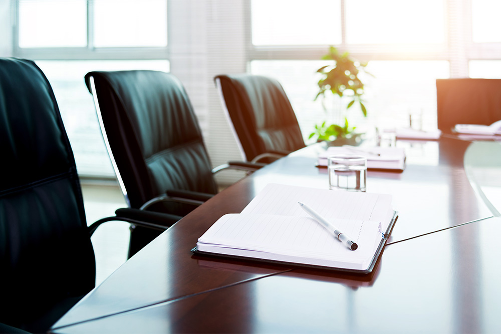 Abstract image of a boardroom with a conference table and desk chairs.