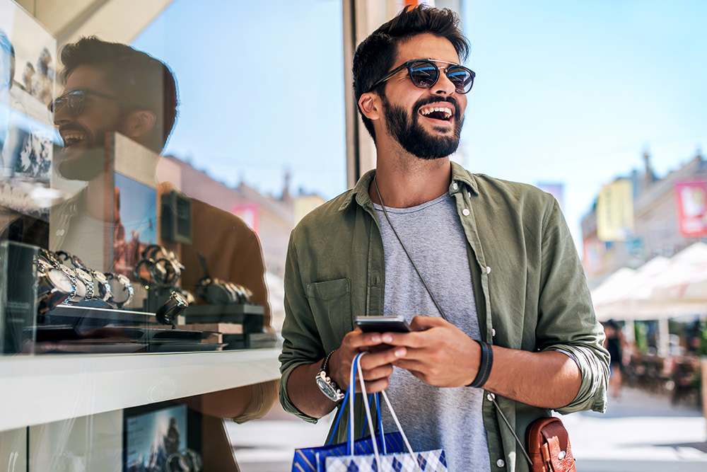 Smiling man looking at watches while shopping