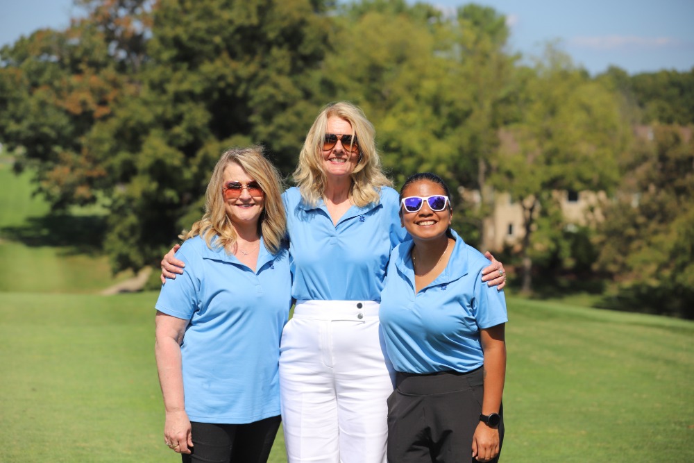 Sarah Landram, Margaret Hersh, and Jennifer Arteaga-Vargas, smile for the camera from the DCCU Cares Foundation 2026 golf tournament. 