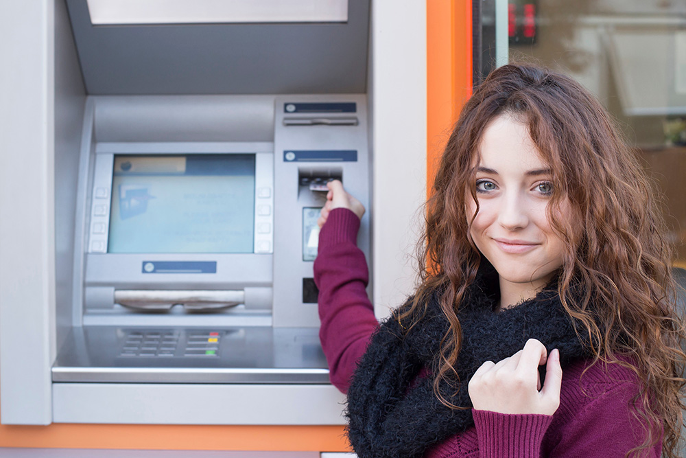 Young woman inserting card into ATM