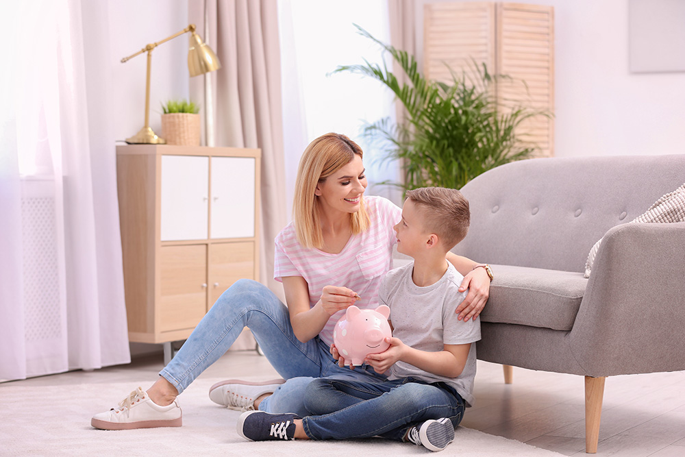 Mother and son inserting money into a piggy bank