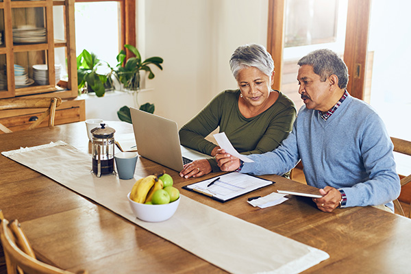 older couple looking at receipts and computer at dining table