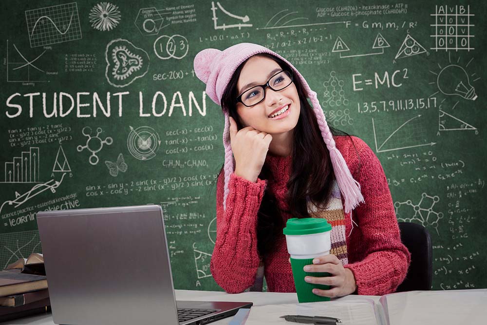 student thinking in front of computer with Student Loan written on the board behind her