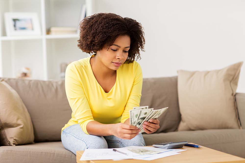 woman counting money in her home