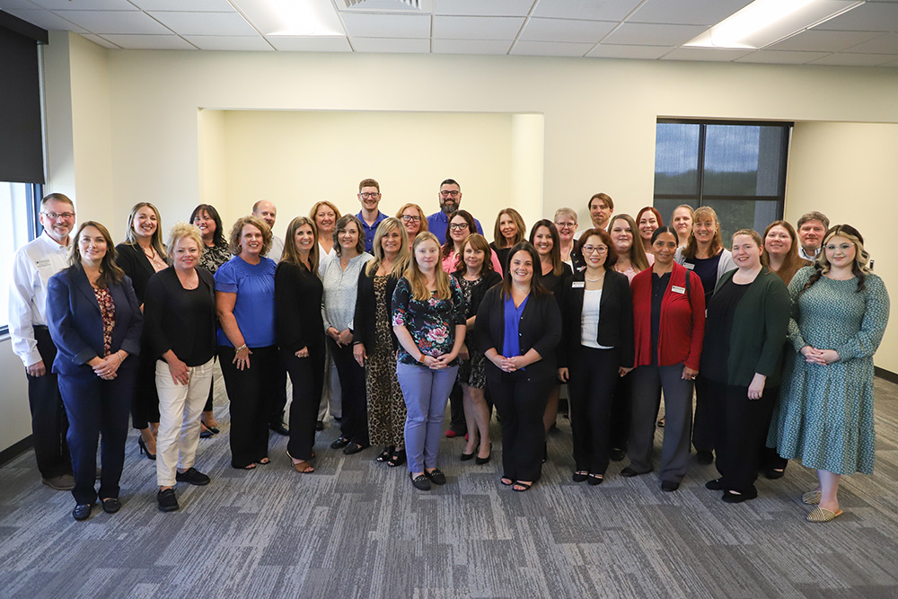 A group of DCCU employees smile and pose for the camera as they are recognized for their service milestones in 2024.