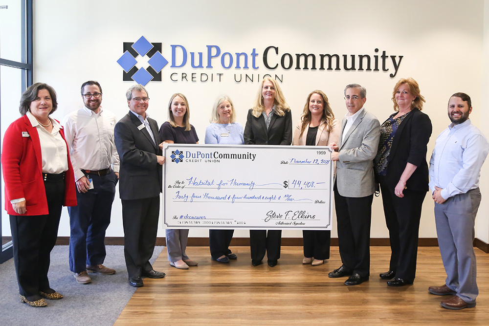 DCCU employees holding large check for Habitat for Humanity