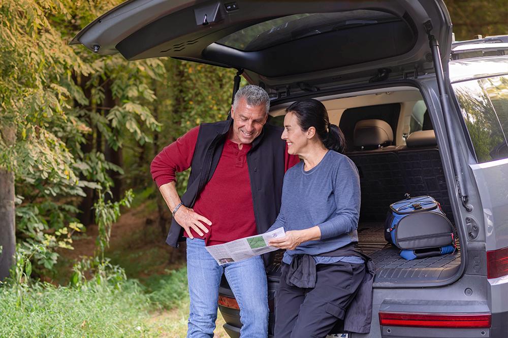 Man and woman looking at map next to car