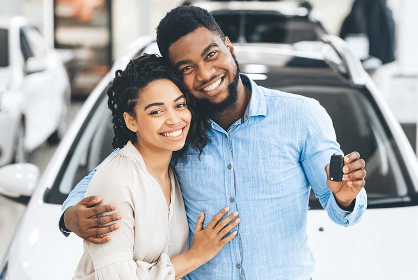 couple holding keys to new car in the dealership