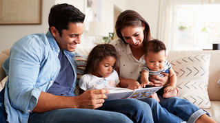 Family of four reading a book together on the couch